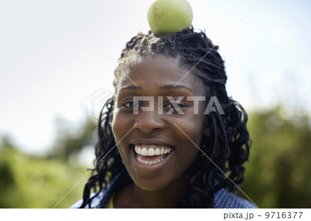 A young woman with a green apple on top of her head.  9716377