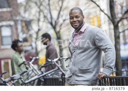 Outdoors in the city in spring. An urban lifestyle. A couple sitting side by side and looking at a phone screen. 9716379