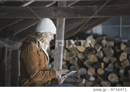 An organic farm in upstate New York, in winter. A woman sitting in an outbuilding using a digital tablet.  9716471