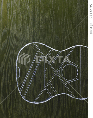 A line drawing image on a natural wood grain background. The sound board and body of a musical instrument, a guitar. A line drawing image on a natural wood grain background. The sound board and body of a musical instrument, a guitar. 9716495