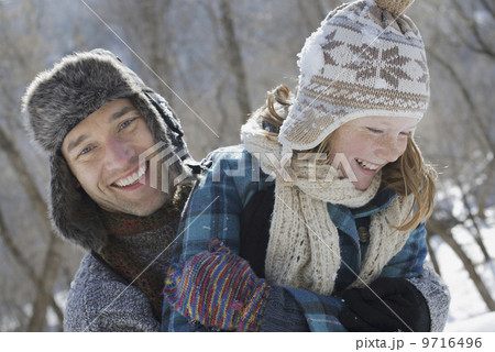 Winter scenery with snow on the ground. A young girl with a bobble hat and scarf and a man hugging her. Winter scenery with snow on the ground. A young girl with a bobble hat and scarf and a man hugging her. 9716496