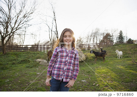 A child, a young girl in the goat paddock enclosure at an animal sanctuary. A child, a young girl in the goat paddock enclosure at an animal sanctuary. 9716860