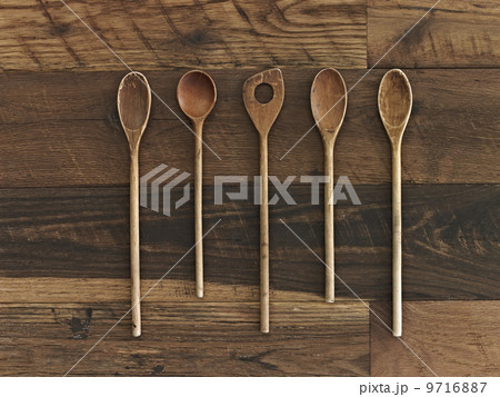 Home cooking. A wooden table with a varied wood grain and colour. Five wooden spoons in a row. 9716887