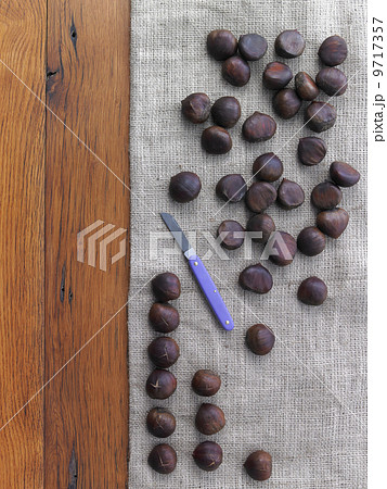 Chestnuts being prepared for roasting. Tabletop, hessian fabric and knife. 9717357