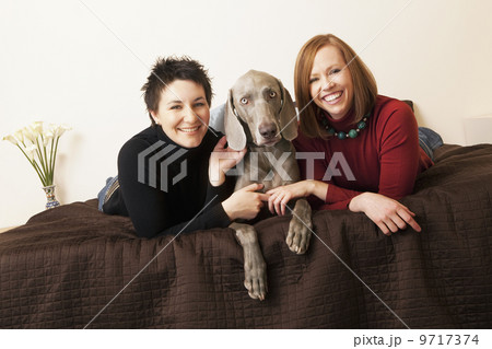 A same sex couple, two women with their Weimaranar pedigree dog between them. A same sex couple, two women with their Weimaranar pedigree dog between them. 9717374