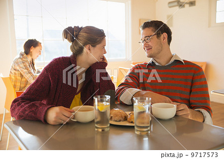 Two young people, a man and a young woman sitting at a counter in a coffee shop. Two young people, a man and a young woman sitting at a counter in a coffee shop. 9717573