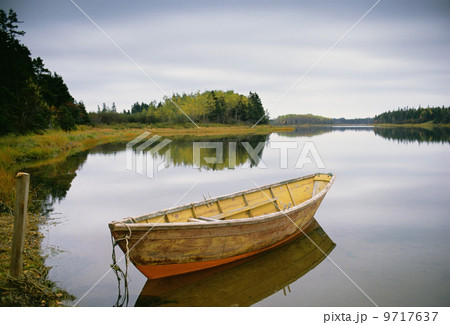 A small wooden dory or rowing boat moored on flat calm water, in Savage harbor on Prince Edward Island in Canada. 9717637