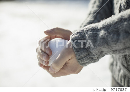 A man holding a large snowball in his bare hands. 9717827