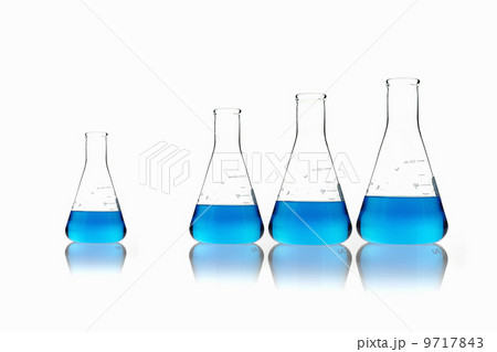 Conical glass scientific flasks holding blue liquids. Lined up in size order, with one set apart. 9717843