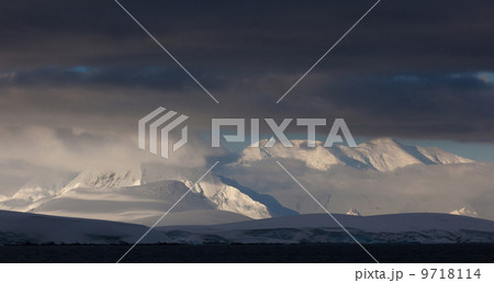 Antarctica. Snow covered peaks with low cloud. 9718114
