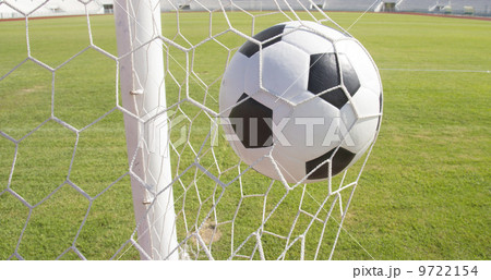 Soccer football in Goal net with green grass field 9722154