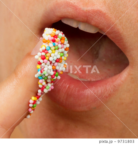 Woman lips and finger with multicolored pearls 9731803