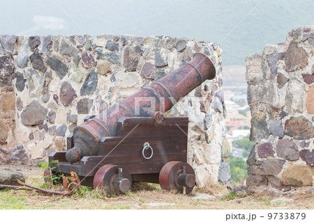 Very old rusted canon on top of an old wall 9733879