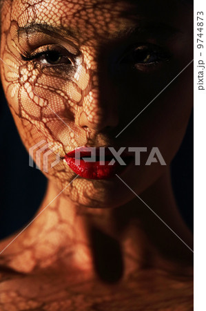 Reflection. Woman in Shadows with Reflection of Openwork Lace on her Face 9744873