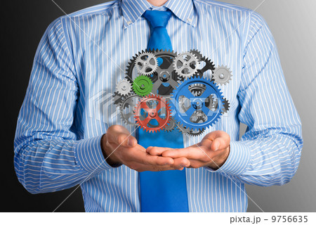 business man holds up a mechanism of gears 9756635