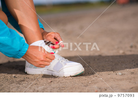 young woman tying shoelaces on sneakers young woman tying shoelaces on sneakers 9757093