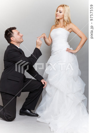 Groom putting a wedding ring on bride's finger Groom putting a wedding ring on bride's finger 9757559