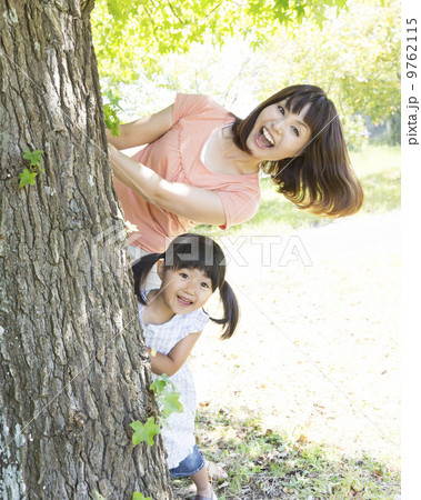 木の幹の後ろから顔を出す親子 9762115