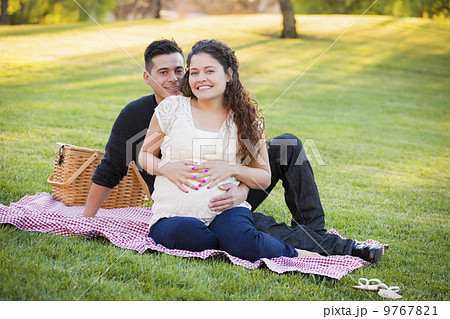 Pregnant Hispanic Couple in The Park Outdoors 9767821