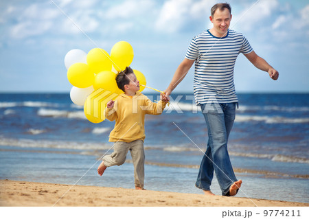 Family with yellow balloons playing on the beach 9774211