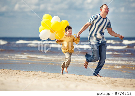Family with yellow balloons playing on the beach 9774212