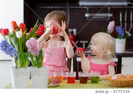 Two little sisters painting Easter eggs 9775550