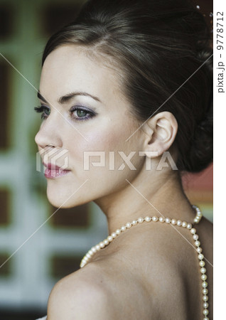 A woman with brown hair, wearing a pearl necklace. 9778712