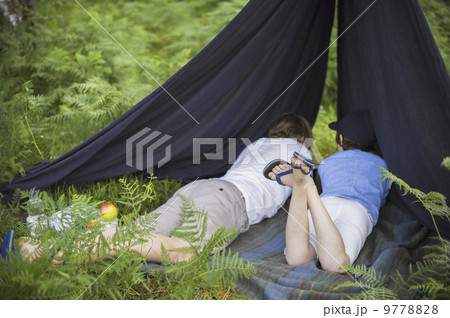 Two boys camping in the New Forest lying under a canvas shelter. Two boys camping in the New Forest lying under a canvas shelter. 9778828