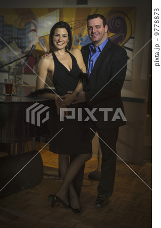 A smartly dressed man and woman side by side by a piano. 9778873