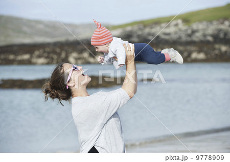A mother raising her baby in the air. At the seaside. 9778909
