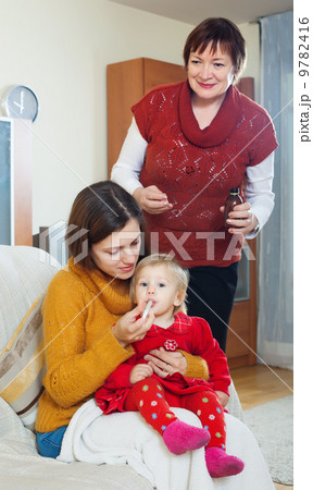 mother with mature grandmother giving medicament to unwell bab mother with mature grandmother giving medicament to unwell bab 9782416