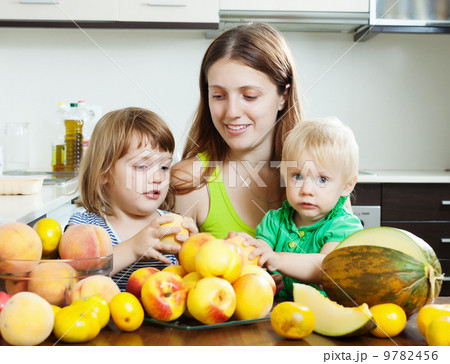 Ordinary woman with daughters eating fruits Ordinary woman with daughters eating fruits 9782456