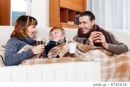Happy parents and teenage son warming near warm calorifer 9782616