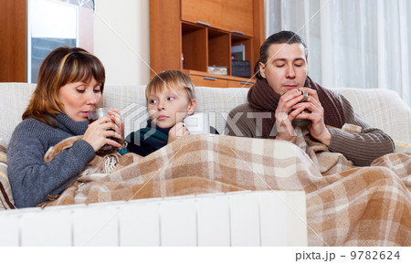 freezing family of three warming near warm radiator freezing family of three warming near warm radiator 9782624