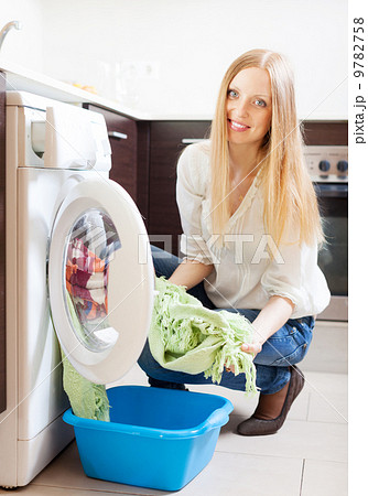 long-haired woman loading clothes into the washing machine 9782758