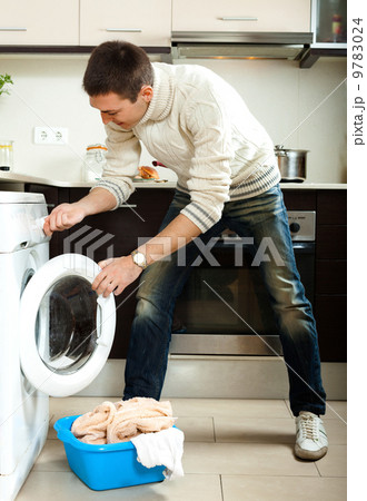 man loading clothes into the washing machine man loading clothes into the washing machine 9783024