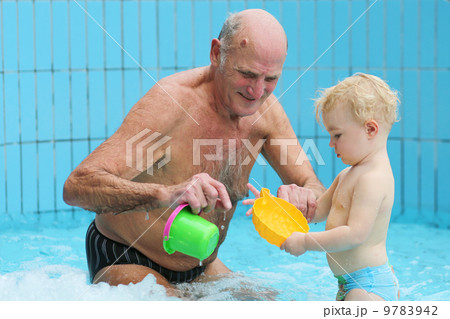 Sportive grandfather with grandchild having fun together playing in swimming pool Sportive grandfather with grandchild having fun together playing in swimming pool 9783942