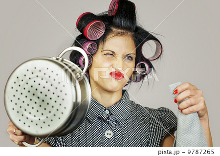 Housewife with a kitchen pot on grey background Housewife with a kitchen pot on grey background 9787265