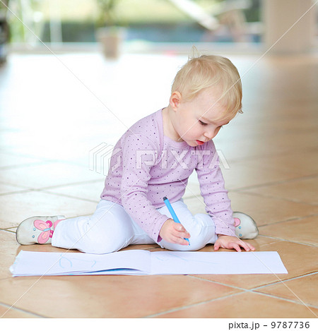 Funny lovely baby girl plays indoors drawing with colorful pencils sitting on tiles floor  9787736