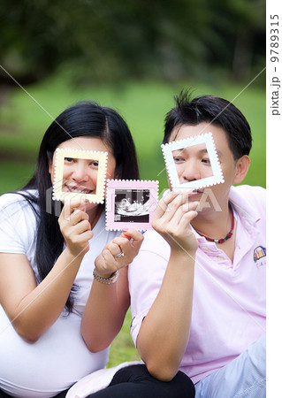 Happy asian-chinese pregnant couple with ultrasound baby photo. 9789315