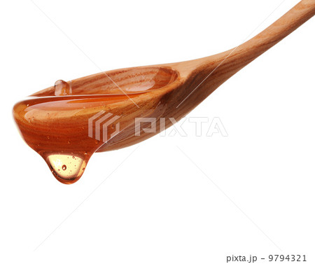 Honey dripping from a wooden honey dipper isolated on white back 9794321