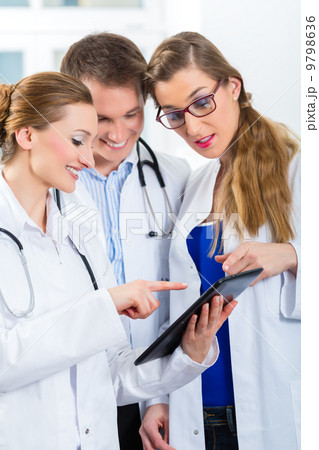 Team of young doctors in clinic with tablet computer Team of young doctors in clinic with tablet computer 9798636