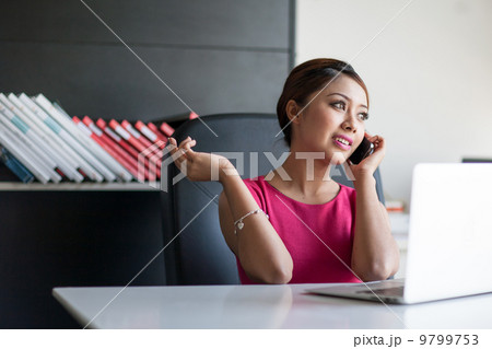 a lady talking on the phone in the office 9799753