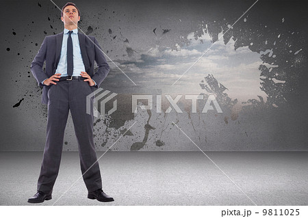 Composite image of serious businessman with hands on hips 9811025