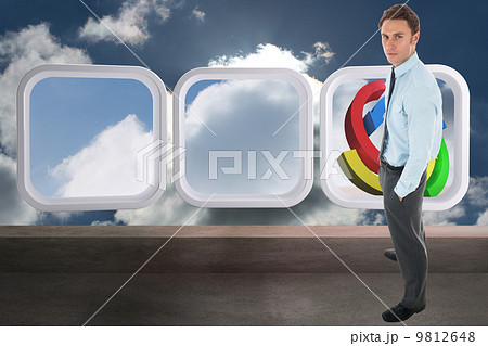 Composite image of serious businessman standing with hands in po 9812648