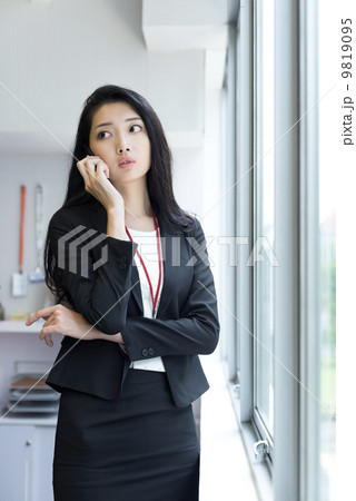 Young business woman using mobile phone outside office cubicle Young business woman using mobile phone outside office cubicle 9819095