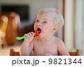 Funny happy healthy toddler sitting in high feeding chair eating cherry tomato 9821344