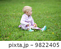 Lovely baby girl in a beautiful kimono suit sitting on a grass in the middle of a park  9822405