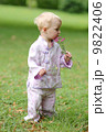 Adorable baby girl in beautiful kimono set is standing in a park with flowers in her hand  9822406