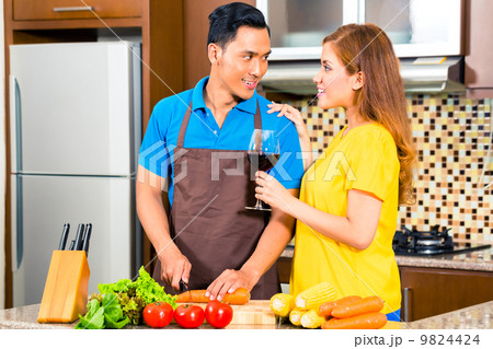 Asian couple preparing food in domestic kitchen 9824424